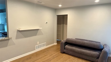 Living area with wood finished floors, a textured wall, and recessed lighting