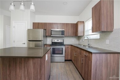 Kitchen featuring sink, stainless steel appliances, tasteful backsplash, light hardwood / wood-style flooring, and decorative light fixtures