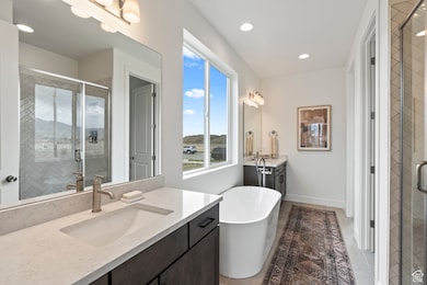 Bathroom with a shower stall, two vanities, a soaking tub, recessed lighting, and light tile patterned flooring