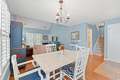 Dining space with lofted ceiling, light wood-style floors, stairs, a chandelier, and a textured ceiling
