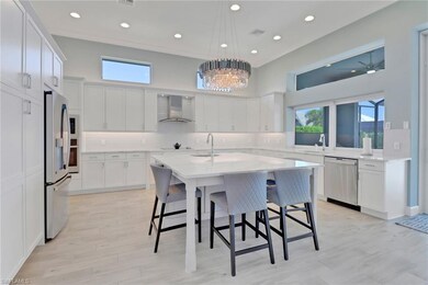 Kitchen with wall chimney range hood, stainless steel appliances, a sink, a kitchen bar, and a center island with sink