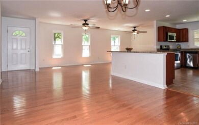 Open floor plan with hardwood floors, ceiling fans