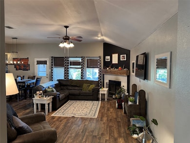 Open-concept living room featuring a ceiling fan and wood-burning fireplace.