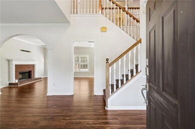 Entryway featuring crown molding, dark wood-style flooring, stairs, a brick fireplace, and a towering ceiling