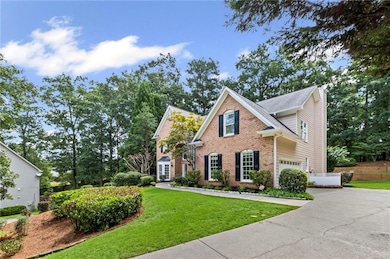 Traditional home featuring brick siding, driveway, a garage, a chimney, and a front lawn