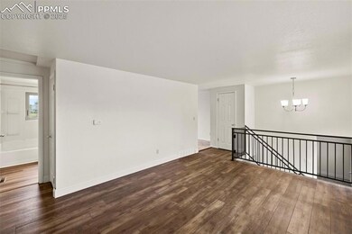 Spare room with a chandelier and dark wood-style flooring