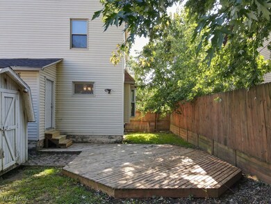 Back of property with entry steps, a wooden deck, and a shed