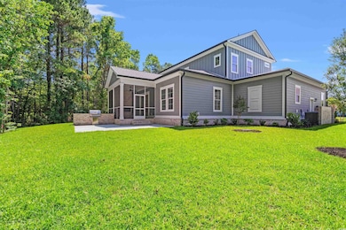 Back of property featuring board and batten siding, a sunroom, a lawn, a patio, and central air condition unit