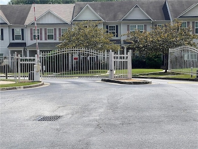 View of asphalt street featuring a gated entry, a gate, and curbs