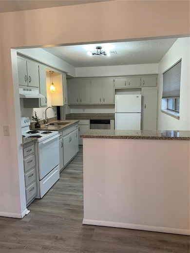 Kitchen with stove, refrigerator, light wood-style floors, a textured ceiling, and extractor fan