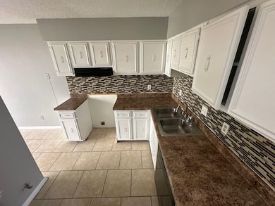 Kitchen with tasteful backsplash, sink, white cabi