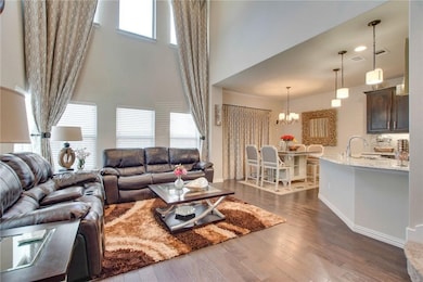 Living room featuring dark wood-style flooring, a chandelier, and a high ceiling