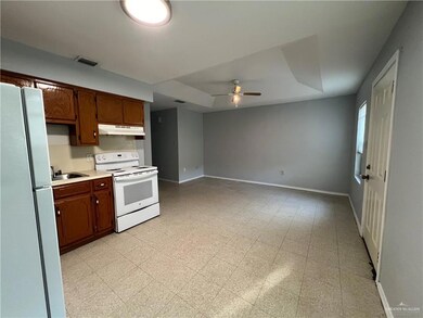 Kitchen with white appliances, under cabinet range hood, light countertops, ceiling fan, and light floors