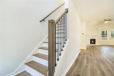 Stairway with ceiling fan, vaulted ceiling, a warm