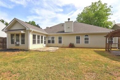 Rear view of house with a chimney, a lawn, a patio