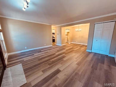 Unfurnished bedroom featuring crown molding, a chandelier, dark wood-style floors, and a closet