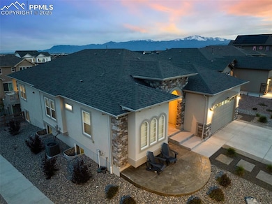 View of front of home with stone siding, stucco siding, a shingled roof, a mountain view, and driveway