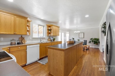 Kitchen with open shelves, light wood finished floors, crown molding, dishwasher, and a center island