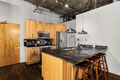 Kitchen with stainless steel appliances, dark wood-style floors, pendant lighting, a breakfast bar, and backsplash