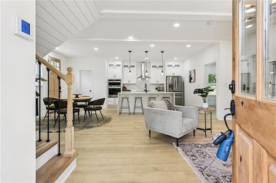 Living area with light wood-style floors, stairway, and recessed lighting