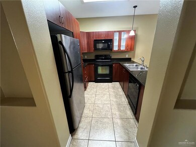 Kitchen with black appliances, a sink, dark countertops, light tile patterned floors, and pendant lighting