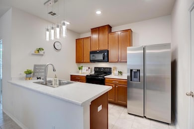 Kitchen with brown cabinetry, visible vents, a pe