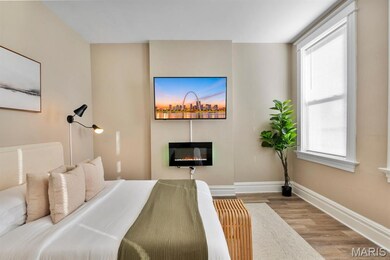Bedroom with wood finished floors and a glass covered fireplace