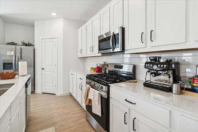 Kitchen featuring appliances with stainless steel finishes, white cabinets, decorative backsplash, light wood-style floors, and recessed lighting