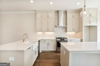 Kitchen featuring stainless steel appliances, wall chimney range hood, a sink, a peninsula, and dark wood finished floors