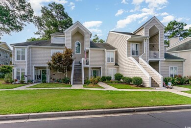 View of property with a balcony and a front lawn