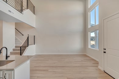 Foyer entrance featuring a towering ceiling, light wood-style floors, and stairs