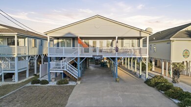 Back of property featuring a carport, concrete driveway, stairs, and a wooden deck