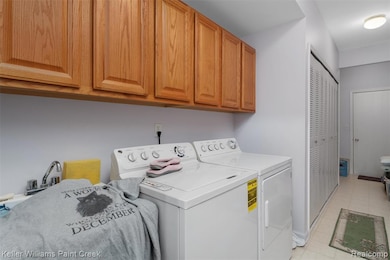 Washroom featuring separate washer and dryer, cabinet space, and light tile patterned flooring