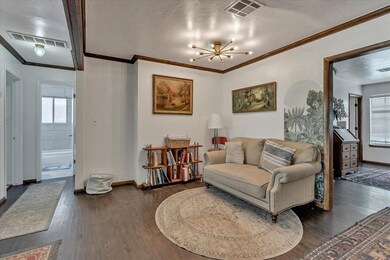Dining area with crown molding, wood finished floors, baseboards, and a chandelier