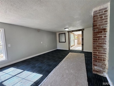 Empty room featuring carpet and a textured ceiling
