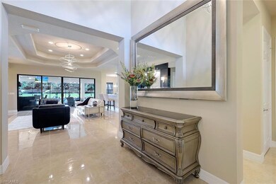 Hallway featuring a raised ceiling and a chandelie