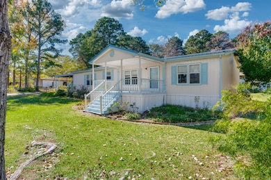 Manufactured / mobile home with covered porch, a front yard, and stairway