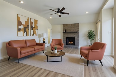 Living area with a fireplace, light wood finished floors, vaulted ceiling, ceiling fan, and recessed lighting