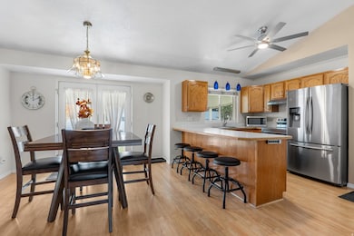 Kitchen featuring stainless steel appliances, light countertops, a peninsula, a breakfast bar, and hanging light fixtures