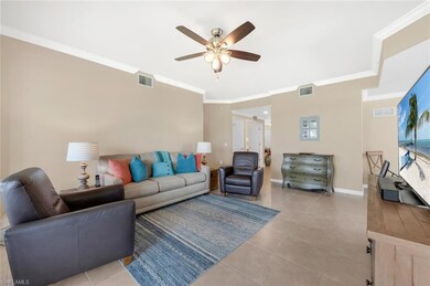 Tiled living room with a ceiling fan, ornamental molding, and baseboards