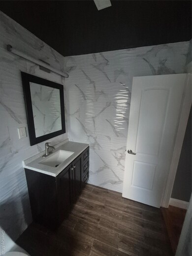 Bathroom with vanity, dark wood finished floors, and tile walls
