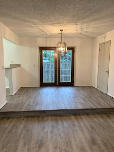 Doorway to outside featuring a textured ceiling, wood finished floors, and a chandelier