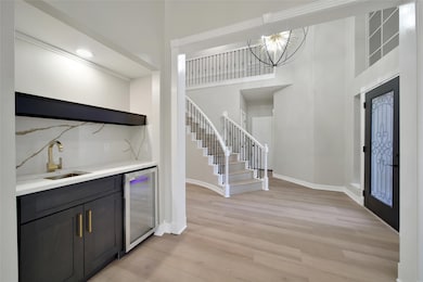 Wet bar with new cabinets, wine fridge, sink, faucet, quartz countertop and backspalsh, and shelf