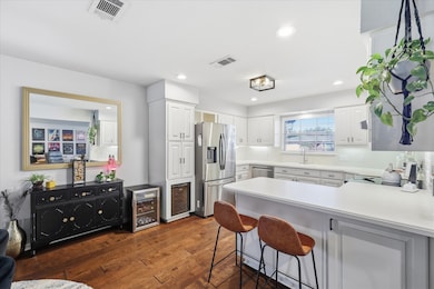 Kitchen featuring a peninsula, dark wood finished floors, stainless steel appliances, a kitchen bar, and white cabinets
