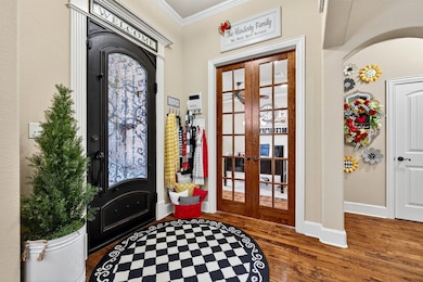 Foyer featuring french doors, wood finished floors, and ornamental molding
