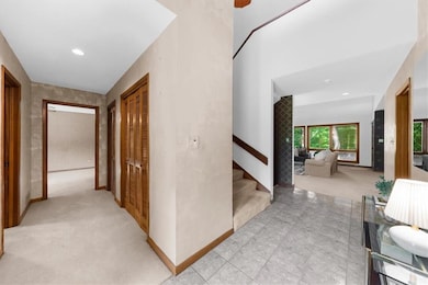 Hallway featuring light carpet, stairs, baseboards