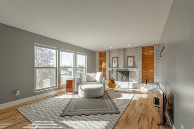 Living room featuring a brick fireplace, light wood-type flooring, and a textured ceiling
