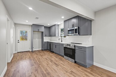 Kitchen with gray cabinetry, backsplash, stainless steel appliances, light wood finished floors, and recessed lighting