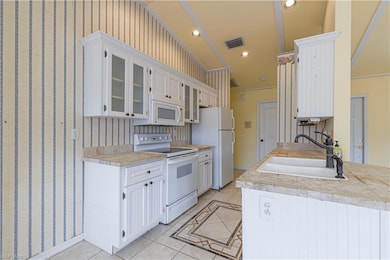 Kitchen featuring white appliances, a sink, light tile patterned floors, glass insert cabinets, and ornamental molding