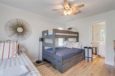Bedroom with crown molding, light wood-style floo